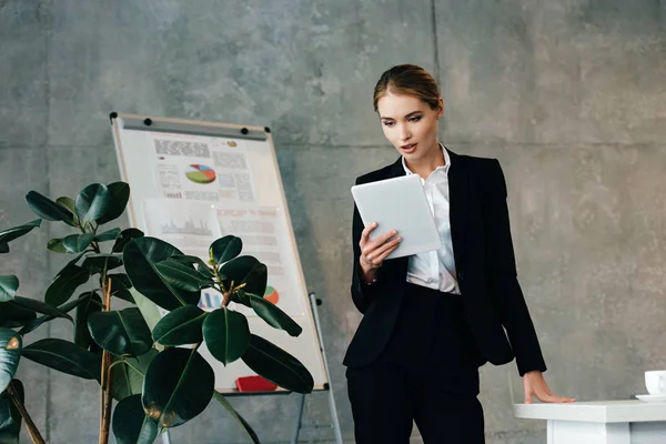 Молодая деловая женщина, используя цифровой планшет, стоя на рабочем месте — стоковое фото