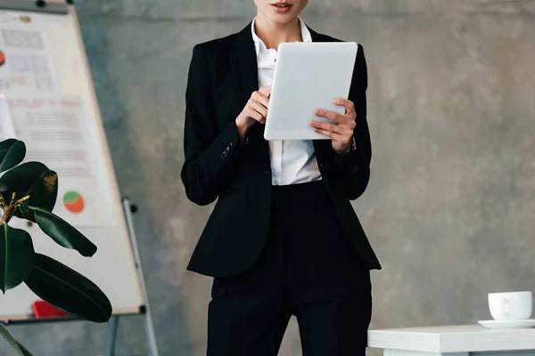 Abgeschnittene Ansicht einer jungen Geschäftsfrau, die am Schreibtisch sitzt und digitales Tablet benutzt — Stockfoto
