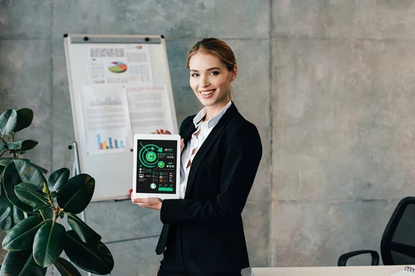 Pretty smiling businesswoman holding digital tablet with inphographics on screen — Stock Photo