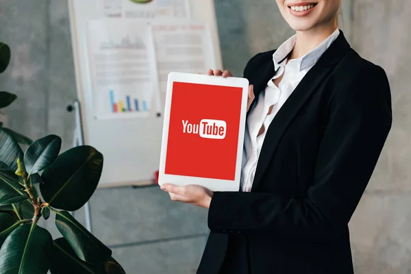 Recortado vista de sonriente mujer de negocios mostrando tableta digital con Youtube en la pantalla - foto de stock