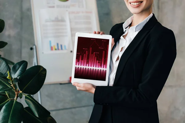 Vue partielle d'une femme d'affaires souriante tenant une tablette numérique avec des graphiques à l'écran — Photo de stock