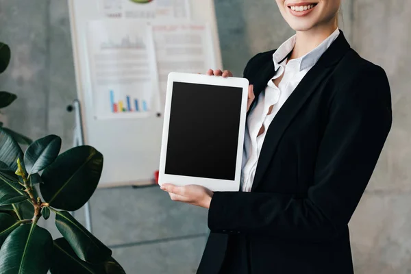 Vue partielle d'une femme d'affaires souriante tenant une tablette numérique avec écran noir — Photo de stock