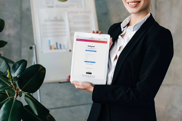 Cropped view of smiling businesswoman holding digital tablet with Instagram on screen — Stock Photo