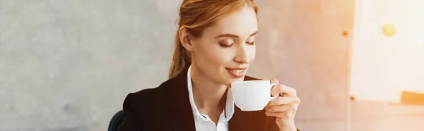Charming businesswoman enjoys drinking coffee with closed eyes — Stock Photo