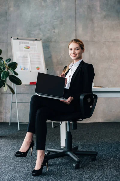 Lächelnde Geschäftsfrau blickt in die Kamera und hält Laptop mit schwarzem Bildschirm — Stockfoto