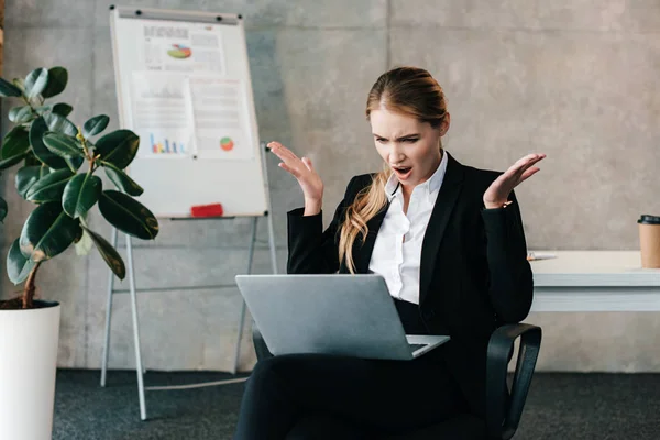Shocked businesswoman looking at laptop and throwing up hands — Stock Photo