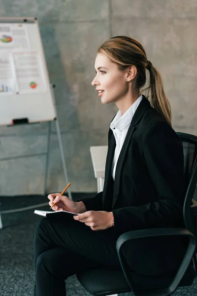 Enfoque selectivo de hermosa mujer de negocios escribiendo en cuaderno - foto de stock