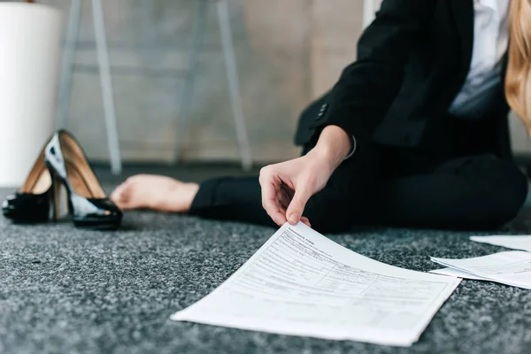 Cropped view of hand woman sitting on floor and holding documents — Stock Photo