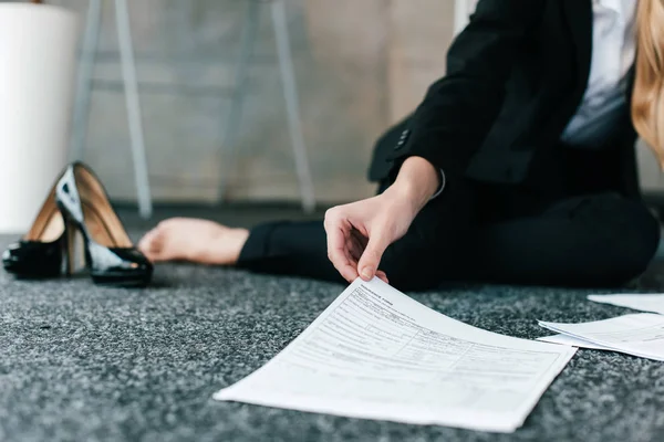 Vue recadrée de la main femme assise sur le sol et tenant des documents — Photo de stock