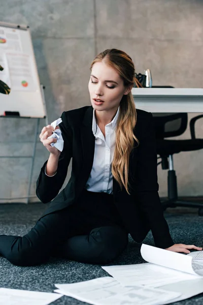 Businesswoman sitting on floor with documents and holding napkin — Stock Photo