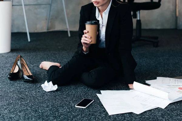 Vue recadrée de femme d'affaires assise sur le sol et tenant du café — Photo de stock