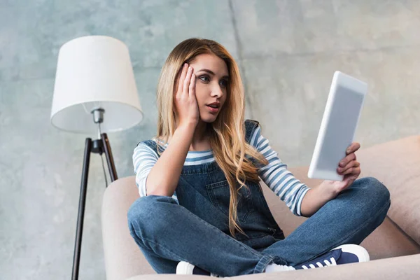 Emotional beautiful woman looking at digital tablet in room — Stock Photo