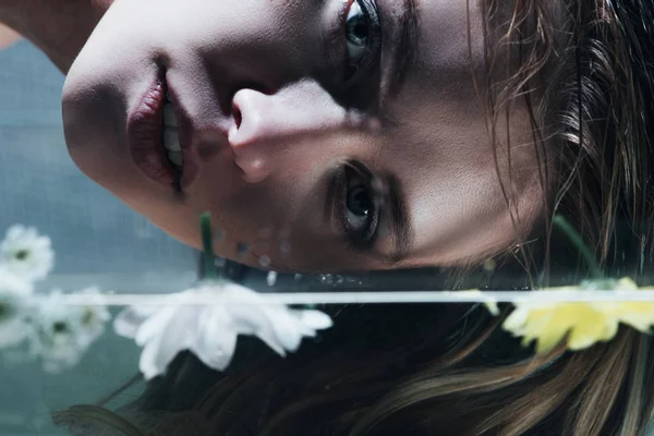 Close up of young woman posing over water with flowers — Stock Photo