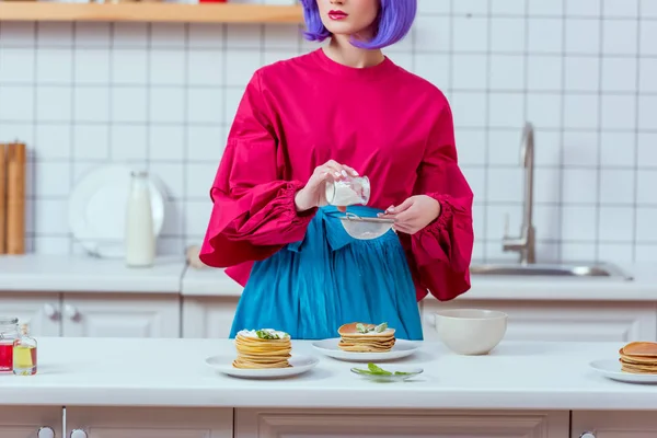 Teilansicht der Hausfrau mit lila Haaren und bunten Kleidern beim Zubereiten von Pfannkuchen in der Küche — Stockfoto