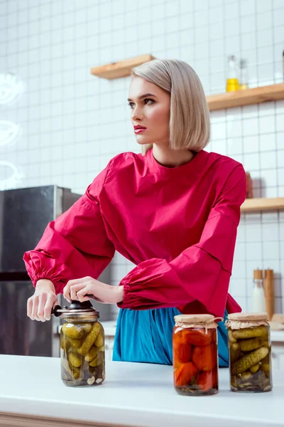 Selektiver Fokus der schönen stilvollen Hausfrau Versiegelung Glas mit eingelegten Gurken in der Küche — Stockfoto