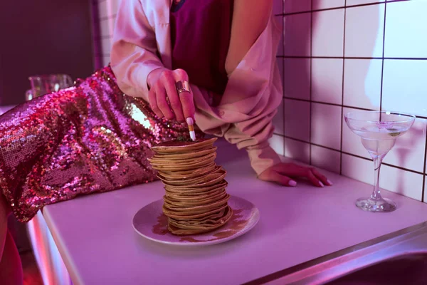 Cropped view of woman putting out cigarette in pancakes in kitchen — Stock Photo