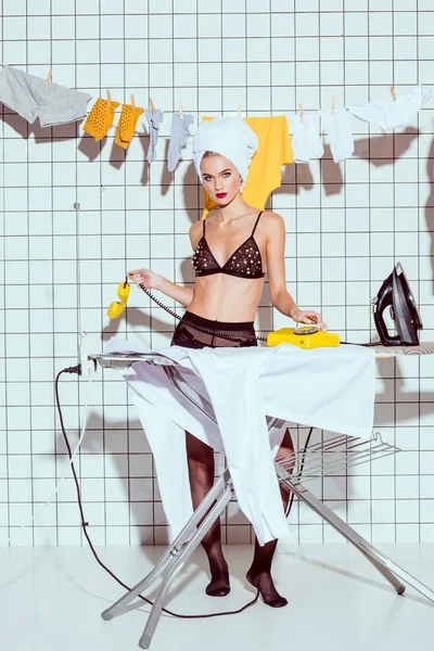 Beautiful housewife dialing retro telephone in bathroom and looking at camera — Stock Photo