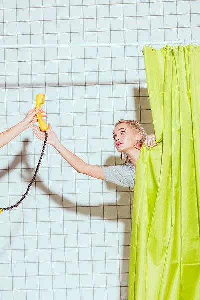 Beautiful woman taking yellow retro telephone handset in shower with green curtain — Stock Photo