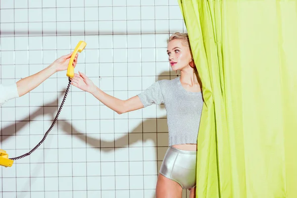 Belle femme élégante prenant téléphone rétro jaune combiné dans la douche avec rideau vert — Photo de stock