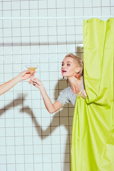 Hermosa mujer detrás de la cortina verde tomando cóctel en la ducha - foto de stock