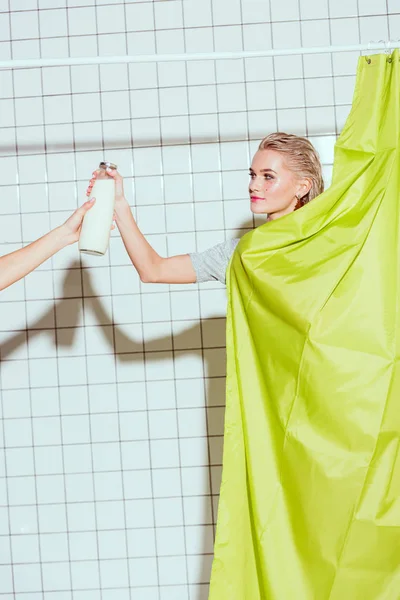 Belle femme prenant bouteille de lait dans la douche avec rideau vert — Photo de stock