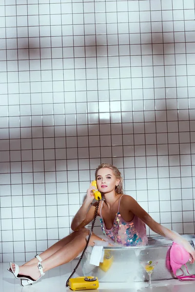 Schöne junge Frau in der Badewanne spricht auf Retro-Telefon im Badezimmer mit Kopierraum — Stockfoto