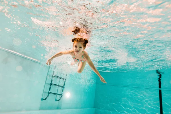 Adorable kid swimming underwater in clear water in swimming pool — Stock Photo