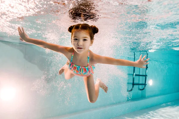 Чарівна дитина плаває під водою у блакитній воді в басейні — стокове фото