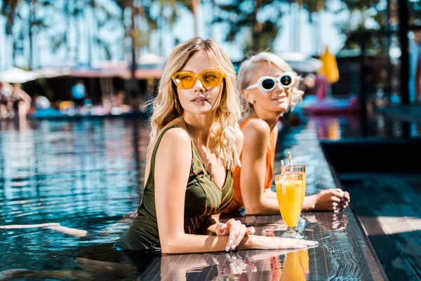 Hermosas mujeres pin up relajarse en la piscina con cócteles - foto de stock
