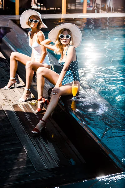 Красивые девушки, сидящие у бассейна со стаканом коктейля — стоковое фото