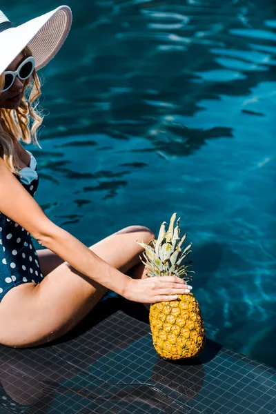 Young woman in swimwear posing with pineapple near swimming pool — Stock Photo