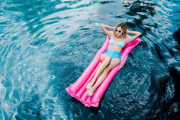 Schöne junge Frau im Badeanzug ruht auf aufblasbarer Matratze im Schwimmbad — Stockfoto