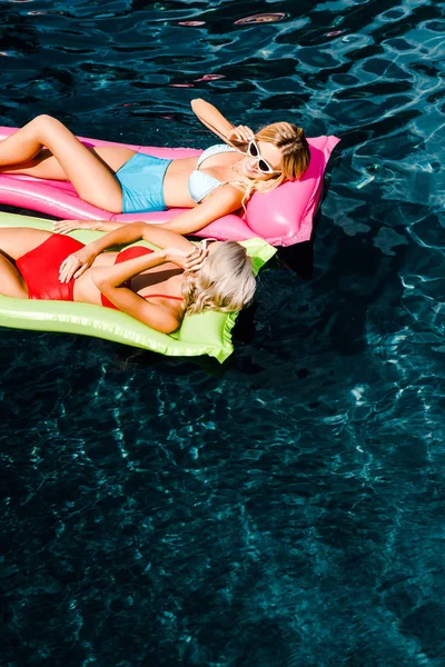 Schöne Frauen sonnen sich und entspannen auf aufblasbaren Matratzen im Schwimmbad — Stockfoto