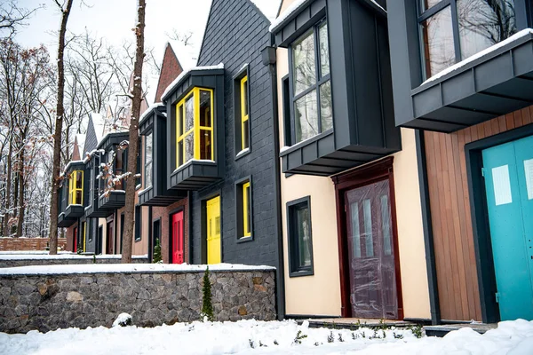 Maisons modernes fantaisie avec de la neige sur le sol près des arbres — Photo de stock