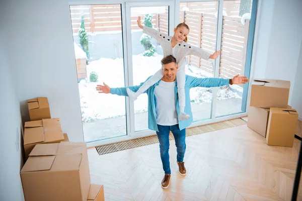 Fröhlicher Vater trägt am Hals lächelnde Tochter beim Spazierengehen im neuen Zuhause — Stockfoto