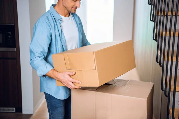 Abgeschnittene Ansicht eines Mannes, der Schachtel in den Händen hält und im neuen Zuhause lächelt — Stockfoto