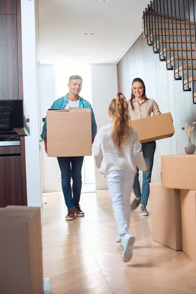 Selektiver Fokus glücklicher Eltern, die Kisten in der Hand halten und ihre Tochter im neuen Zuhause betrachten — Stockfoto