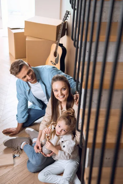 Selective focus of cheerful family sitting on floor in new home — Stock Photo