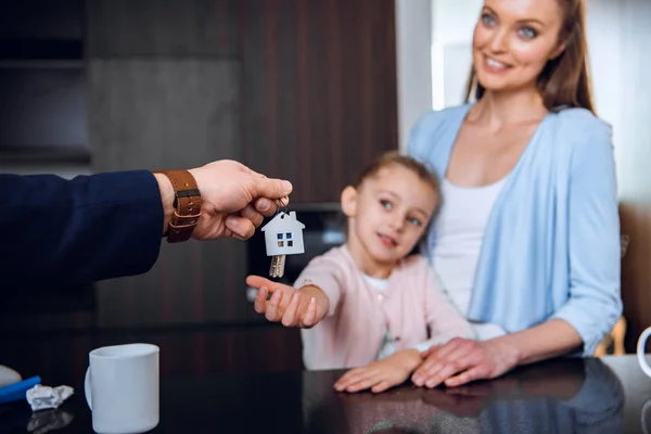 Messa a fuoco selettiva del broker dando casa portachiavi a forma di allegra mamma e figlia — Foto stock