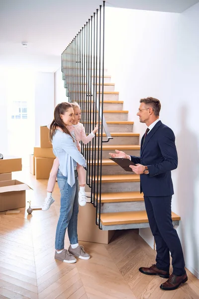 Schöner Makler im Gespräch mit Frau, die süße Tochter in den Armen hält — Stockfoto