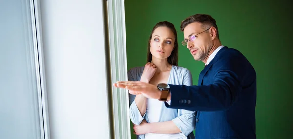 Handsome broker showing something to beautiful woman in new home — Stock Photo