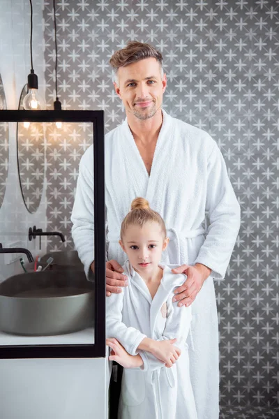 Feliz padre de pie con linda hija y sonriendo en el baño - foto de stock