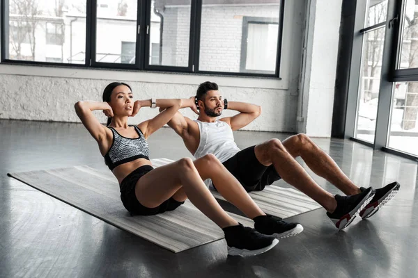 Atlético jovem casal fazendo abs exercício no ioga tapetes no ginásio — Fotografia de Stock