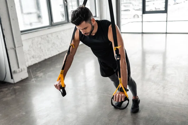 Vista ad alto angolo del giovane muscolare che si allena con bande di resistenza in palestra — Foto stock