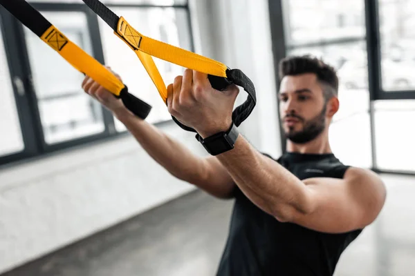 Close-up view of athletic muscular young man in sportswear training with resistance bands in gym — Stock Photo
