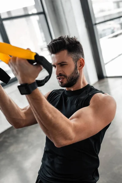 Muskulös konzentrierter junger Sportler beim Training mit Aufhängebändern im Fitnessstudio — Stockfoto