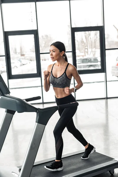 Bella giovane sportiva che corre sul tapis roulant in palestra — Foto stock