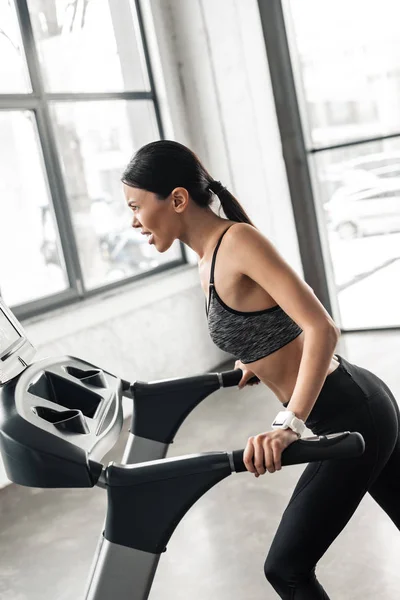 Side view of athletic young woman training on treadmill in gym — Stock Photo