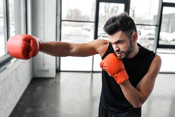 Guapo joven deportivo en el entrenamiento de guantes de boxeo en el gimnasio - foto de stock