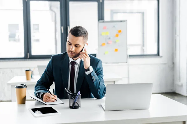 Handsome businessman talking on smartphone in modern office — Stock Photo